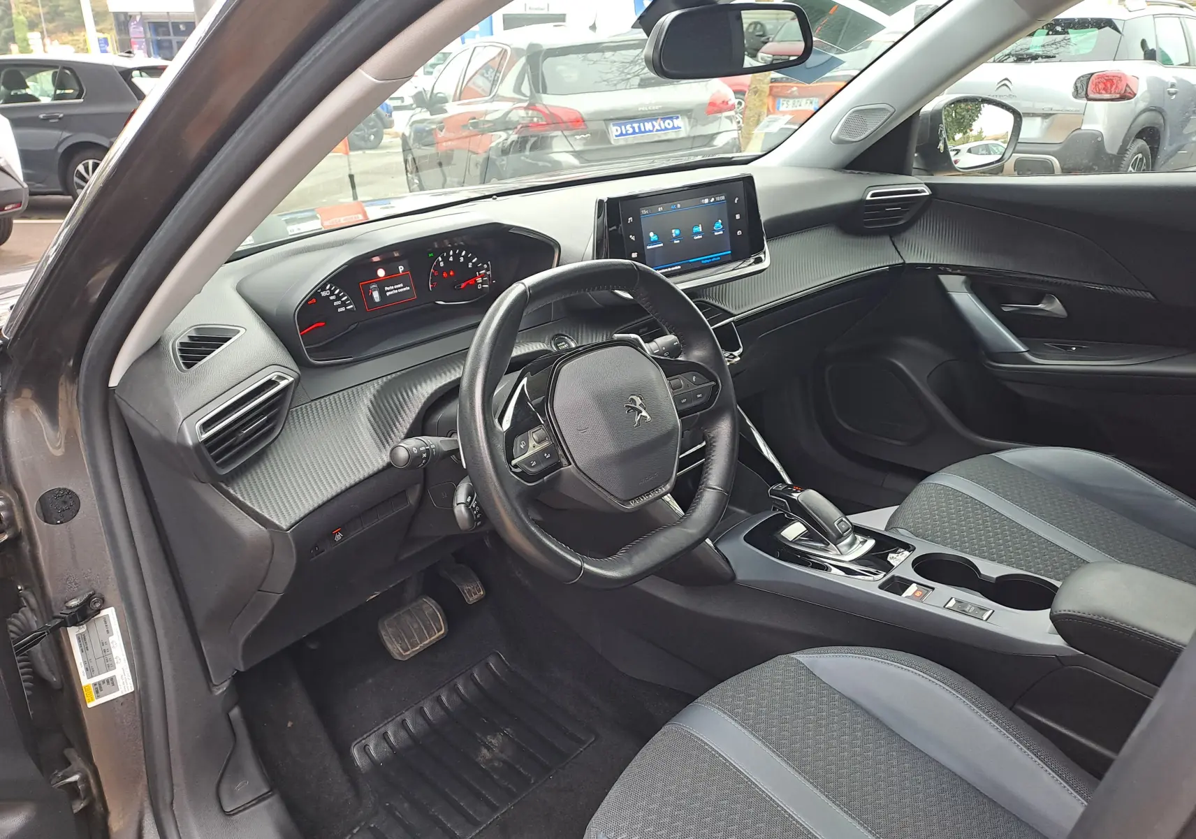 Intérieur de la Peugeot 2008 gris Artense, vue côté conducteur, tableau de bord moderne avec écran tactile et volant compact.
