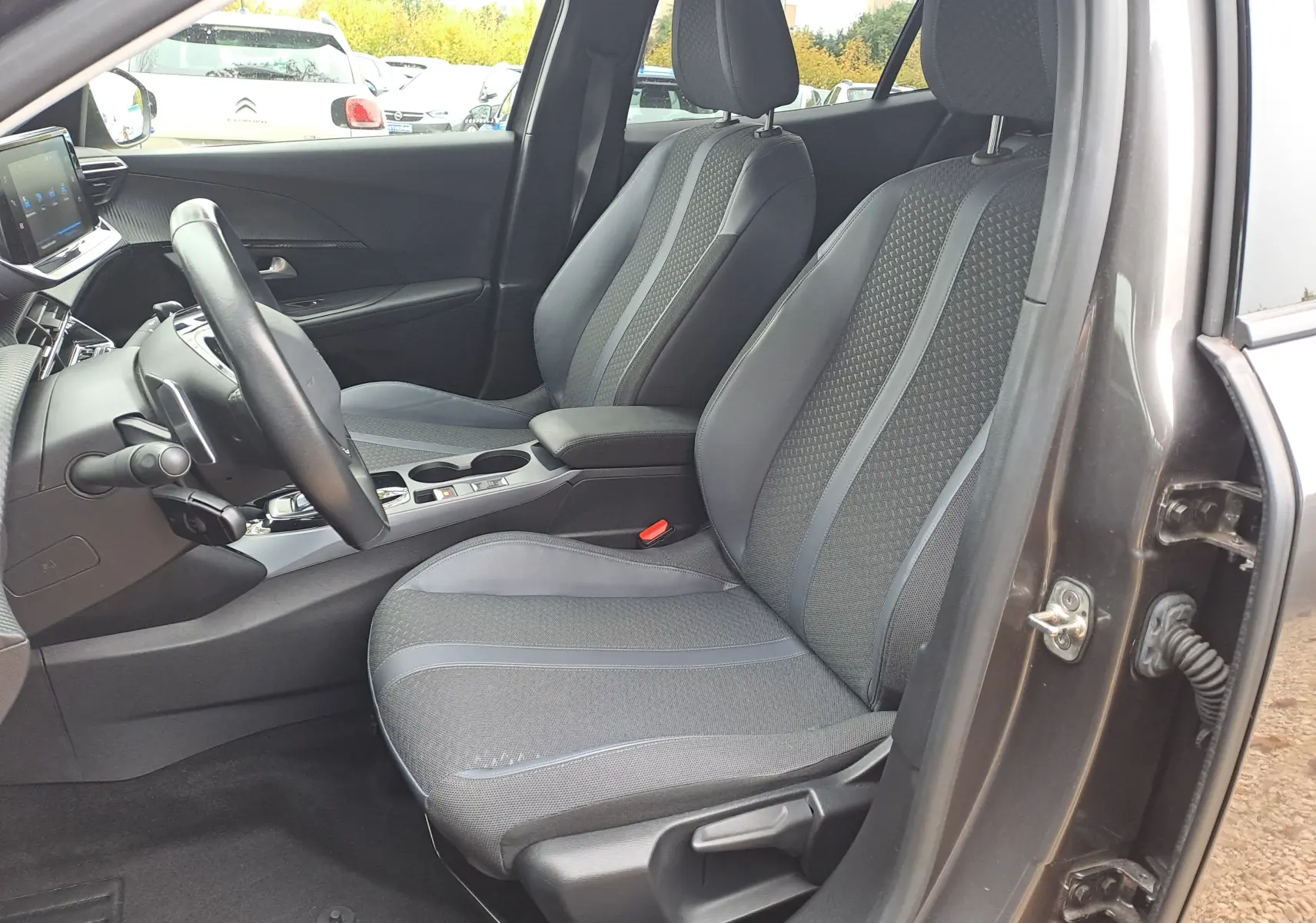 Intérieur côté conducteur du Peugeot 2008 gris Artense 2020, sièges tissu gris avec surpiqûres et console centrale moderne.