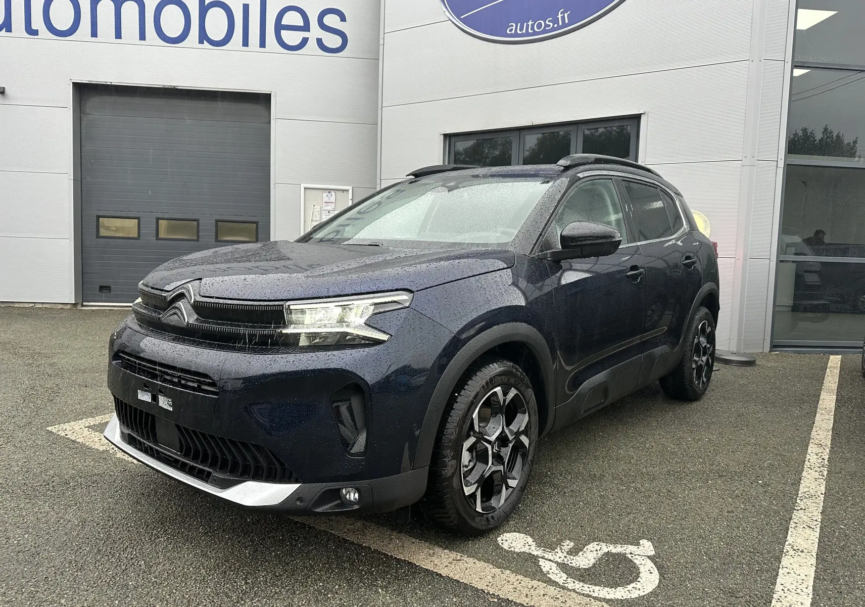 SUV Citroën C5 Aircross Bleu Eclipse vu en 3/4 avant droit sous la pluie avec jantes alliage bi-ton et toit ouvrant.