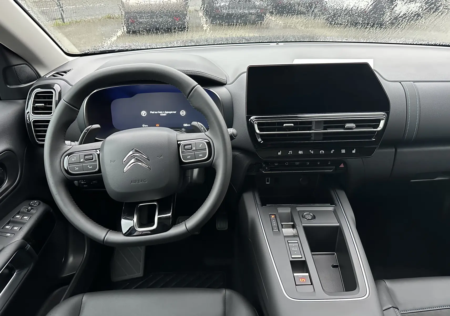 Vue intérieure du tableau de bord et volant noir du Citroën C5 Aircross 2025 avec écran tactile et commandes intégrées au volant.