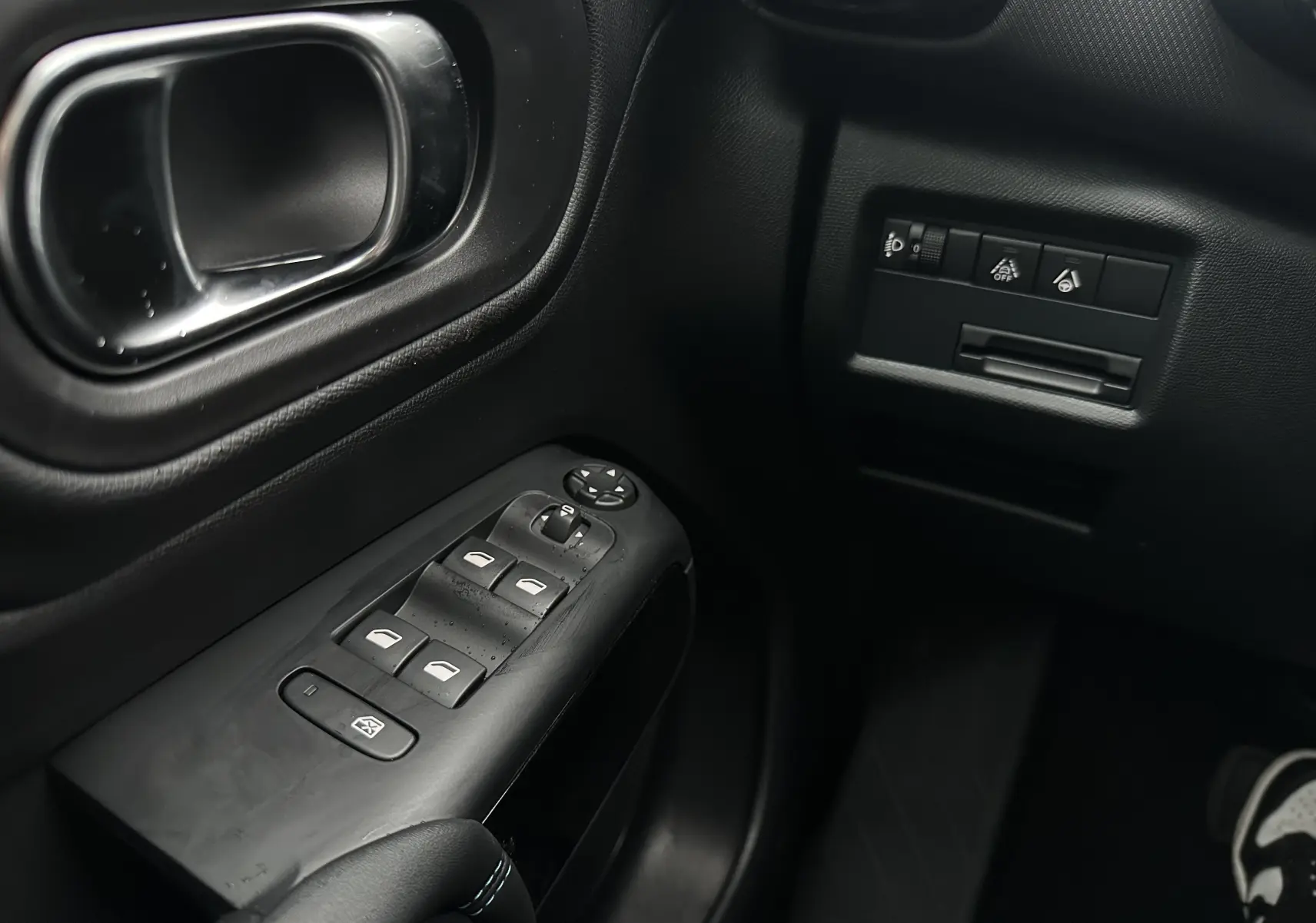 Gros plan sur la commande des vitres et les boutons de réglage côté gauche intérieur noir du Citroën C5 Aircross 2025.