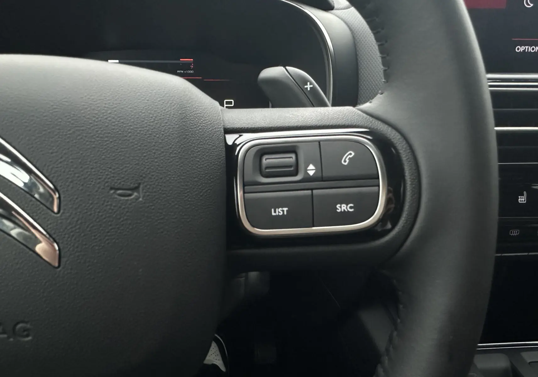 Gros plan sur le volant en cuir noir du Citroën C5 Aircross 2025, avec commandes intégrées côté droit.