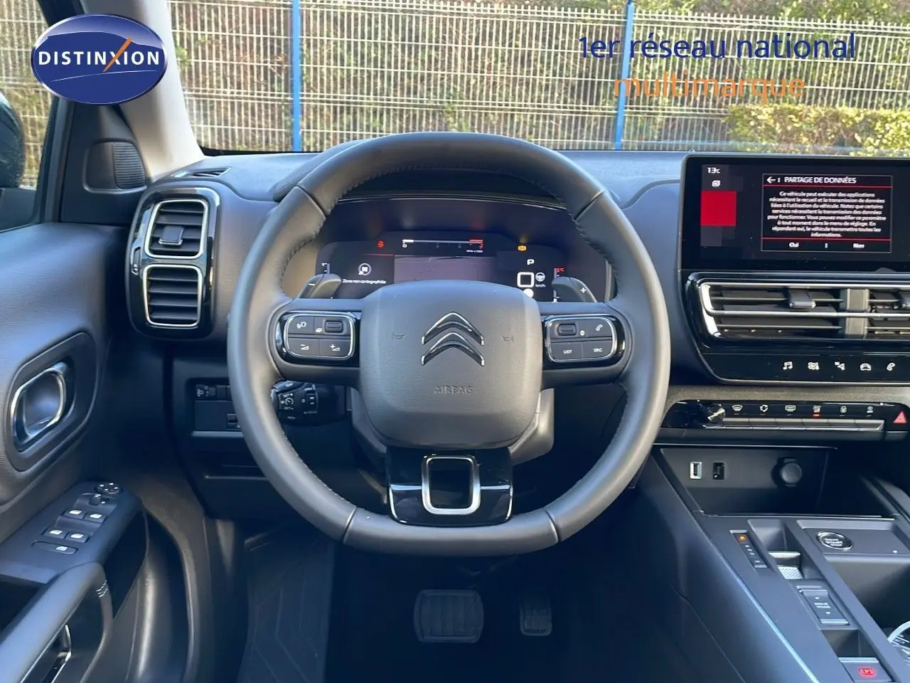 Vue frontale du poste de conduite noir du Citroën C5 Aircross 2025 avec volant multifonction et écran tactile central.