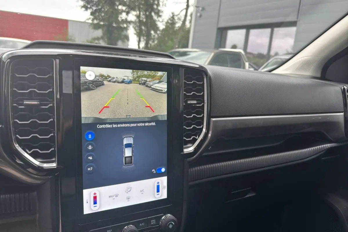 Vue intérieure du tableau de bord du Ford Ranger blanc glacier 2026, avec écran tactile de caméra de recul et commandes climatisation.