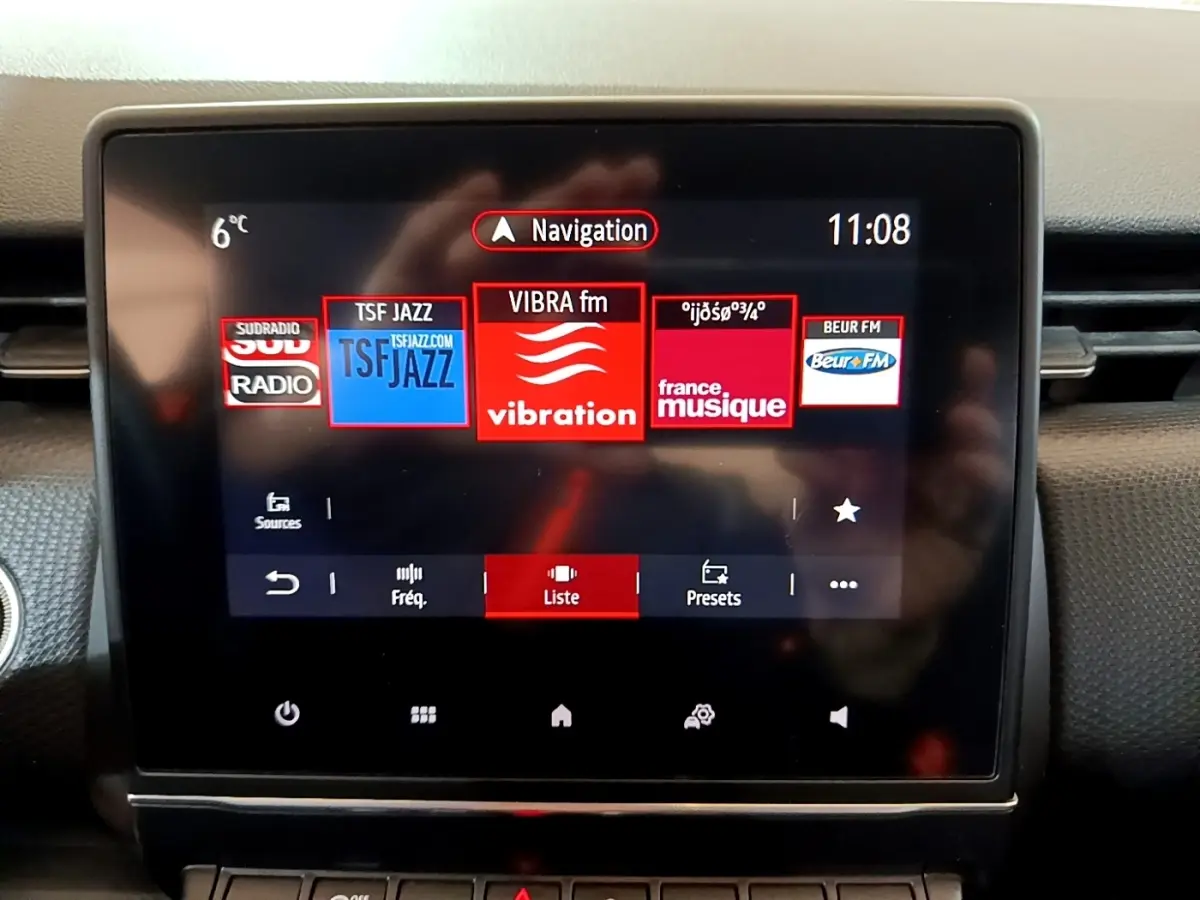 Écran tactile central de la Renault Clio Business TCe 100 blanc, affichant les stations radio et la navigation.