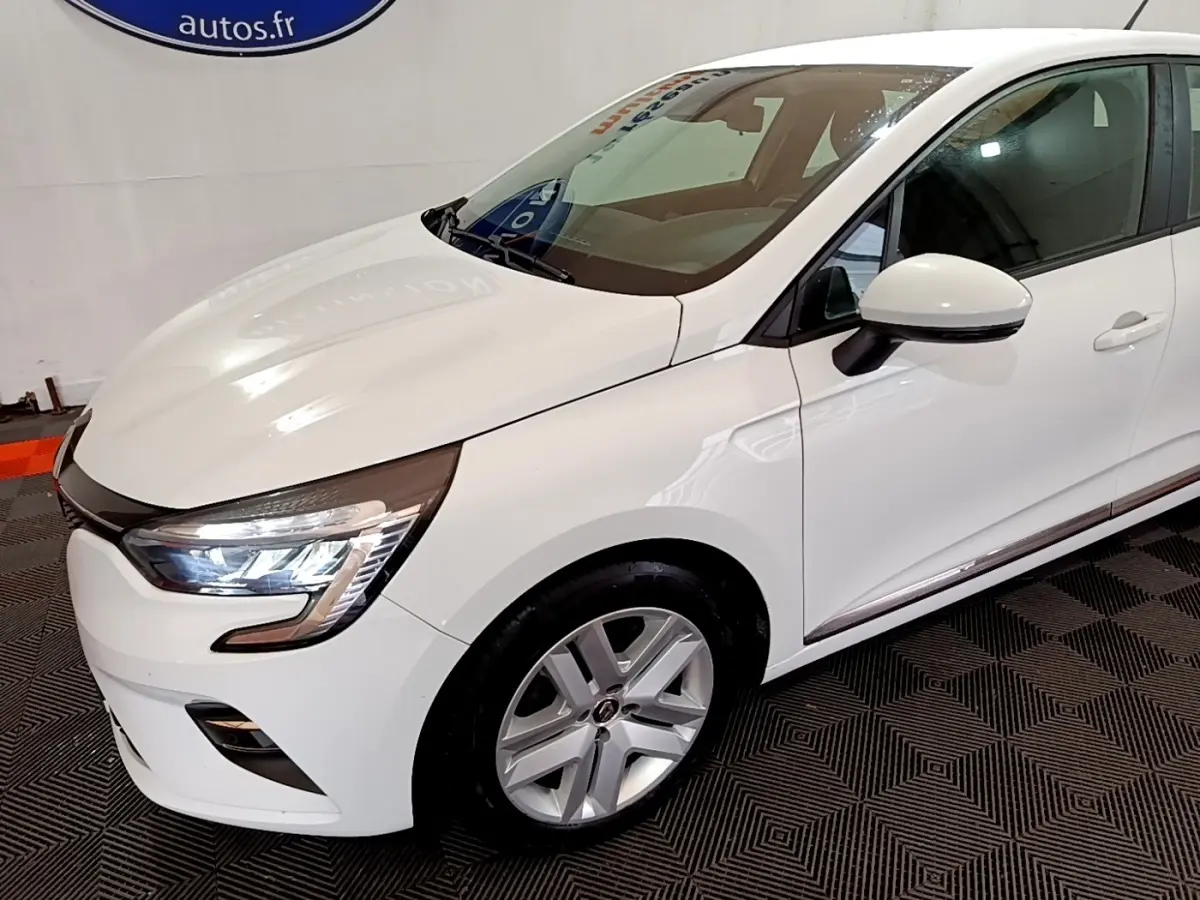 Renault Clio Business TCe 100 blanche vue en 3/4 avant droit, avec phares LED et jantes alliage visibles.