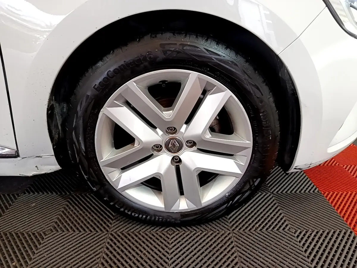 Gros plan sur la roue avant droite d'une Renault Clio blanche, mettant en valeur la jante alliage et le pneu Continental.