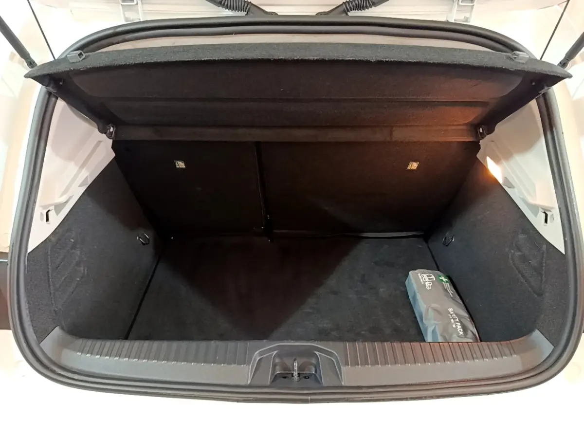 Vue plongeante sur le coffre ouvert blanc d'une Renault Clio 2020, avec un kit de secours visible à droite.