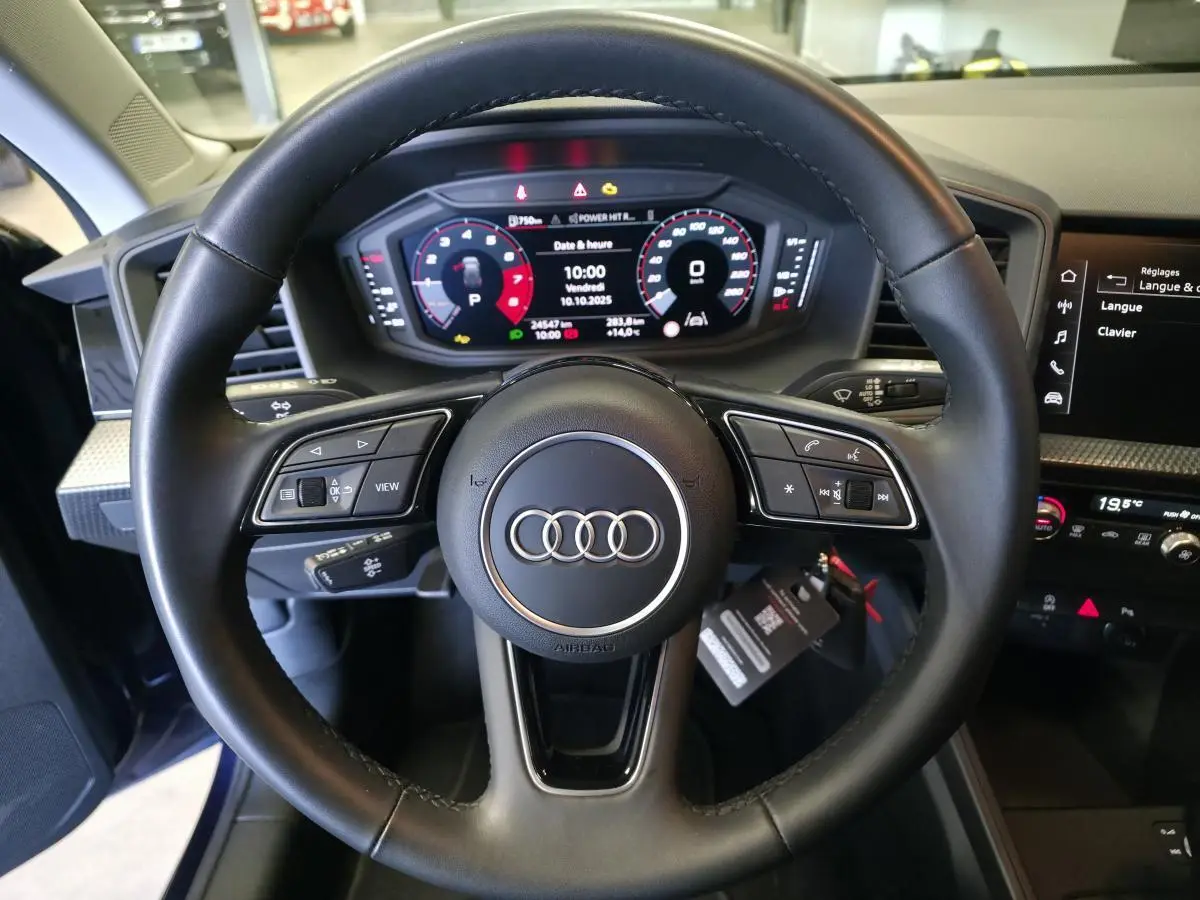 Vue rapprochée du volant cuir multifonctions noir et du tableau de bord digital de l'Audi A1 Sportback 2024.