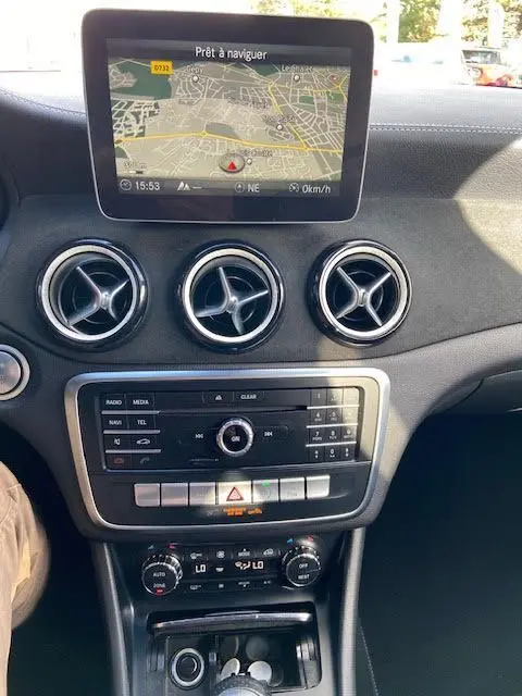 Vue intérieure du tableau de bord d'une Mercedes CLA Shooting Brake 200D WhiteArt Edition avec écran de navigation et aérateurs ronds chromés.