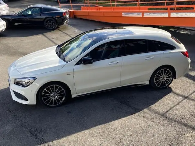 Vue latérale droite d'une Mercedes CLA Shooting Brake 200D WhiteArt blanche avec jantes AMG bicolores et vitres teintées.