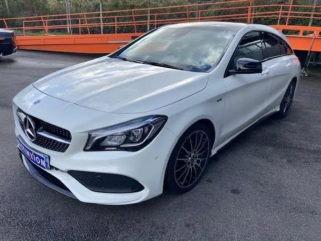 Mercedes Classe CLA Shooting Brake blanche vue en 3/4 avant droit, avec jantes noires et calandre AMG distinctive.