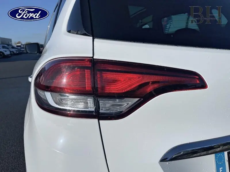 Gros plan sur le feu arrière gauche d'un Renault Scénic blanc nacré avec toit noir étoilé, vue arrière côté gauche.