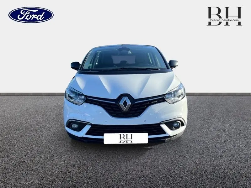 Vue frontale d'un Renault Scénic blanc nacré avec calandre noire et phares LED allumés sur fond neutre.