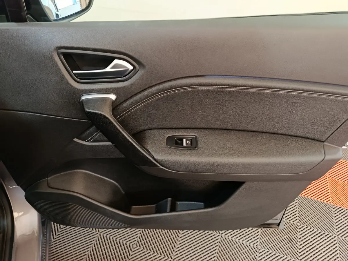 Vue intérieure côté gauche de la porte avant gris foncé du Renault Captur 2024 avec poignée et commande de vitre.