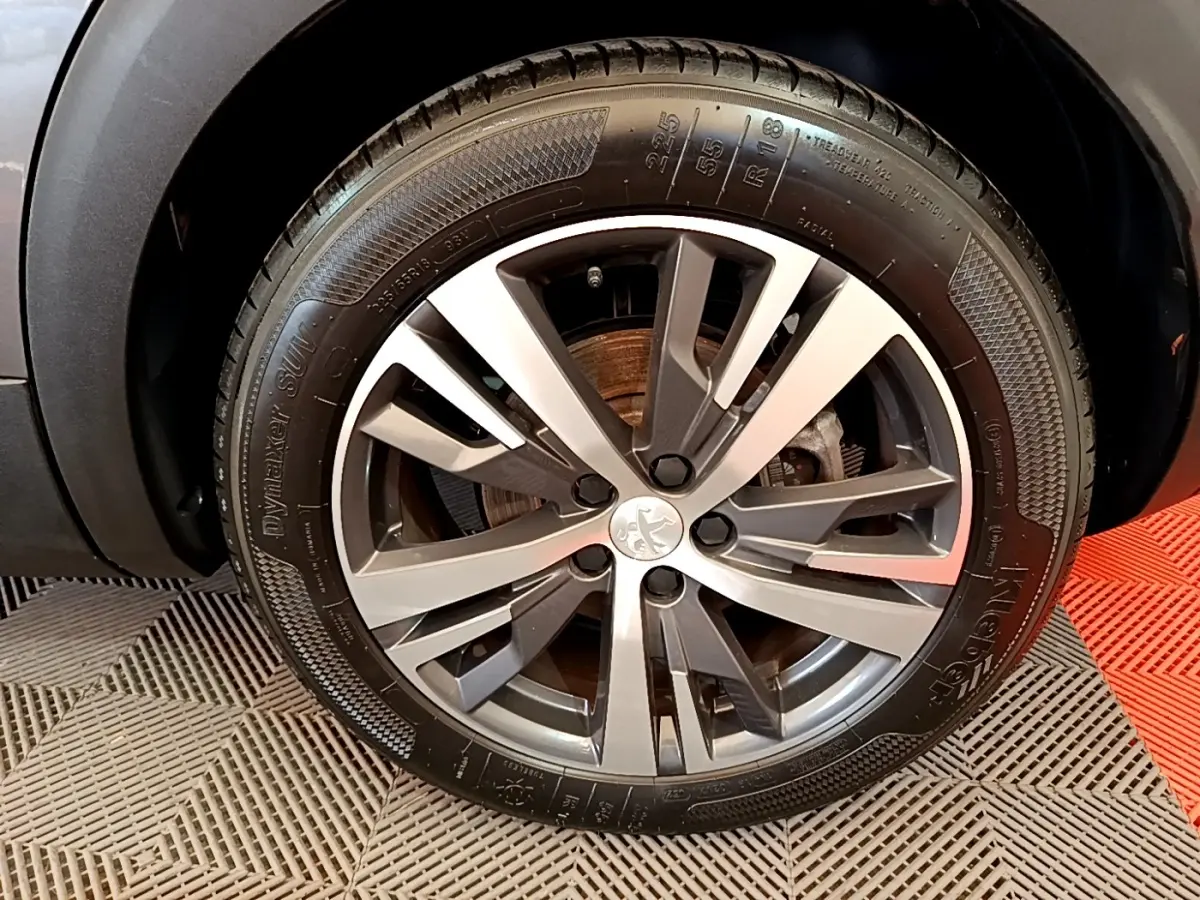 Gros plan sur la roue avant droite du Peugeot 3008 gris foncé, mettant en valeur la jante alliage au design moderne.