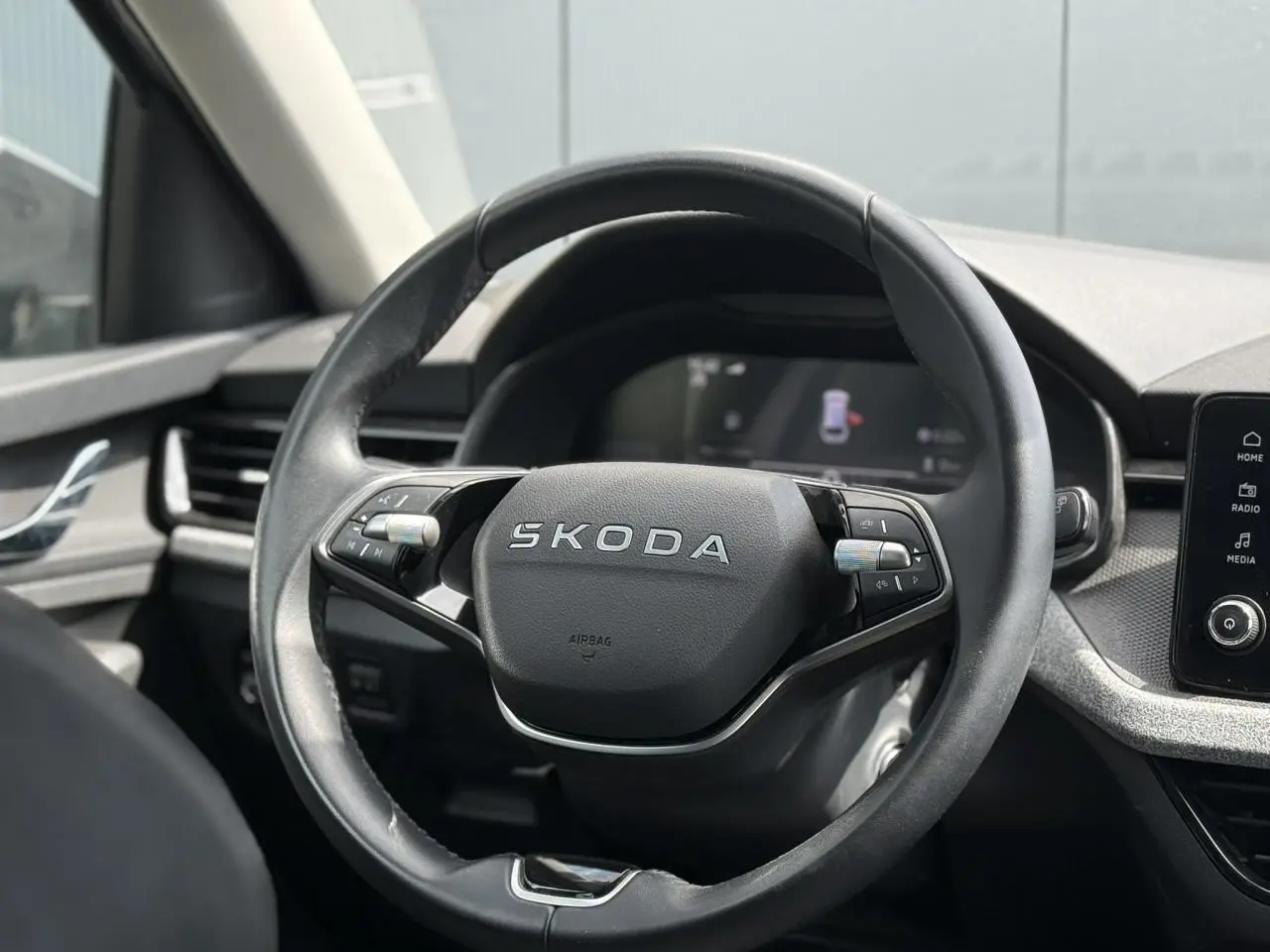 Vue rapprochée du volant en cuir noir marqué SKODA dans l’habitacle moderne d’une Scala gris graphite.