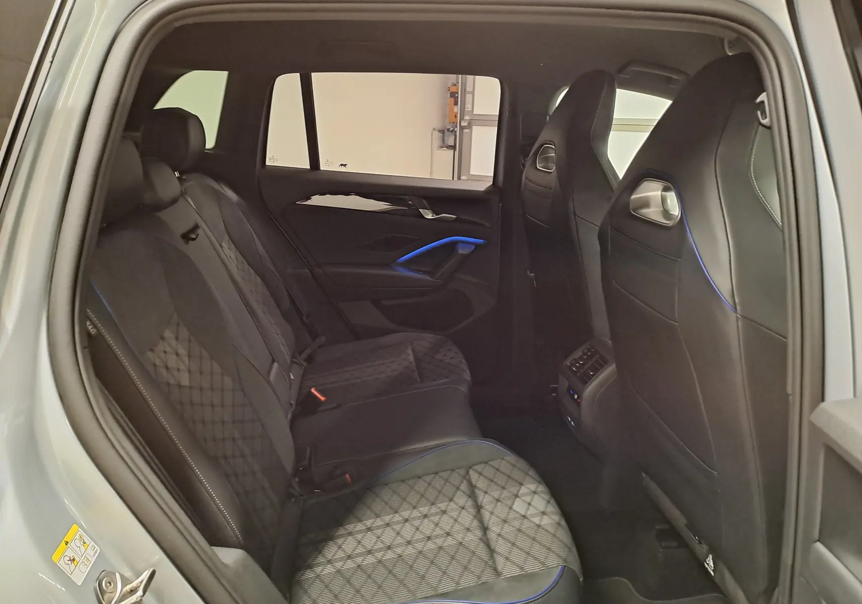 Vue intérieure côté gauche des sièges arrière du Volkswagen Tiguan 2.0 TDI 150 DSG7 R-Line avec surpiqûres bleues.