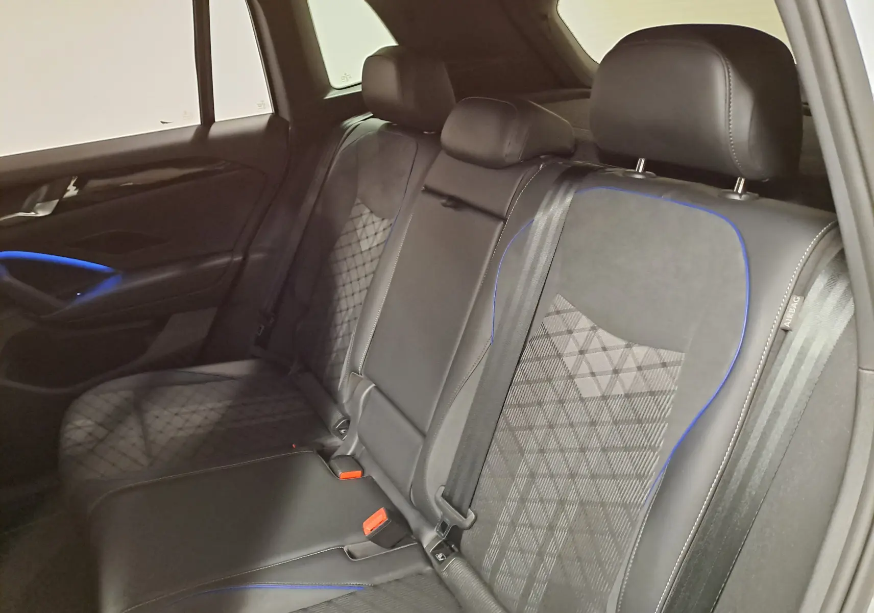 Vue intérieure des sièges arrière en cuir noir avec surpiqûres bleues du Volkswagen Tiguan 2.0 TDI R-Line 2025.