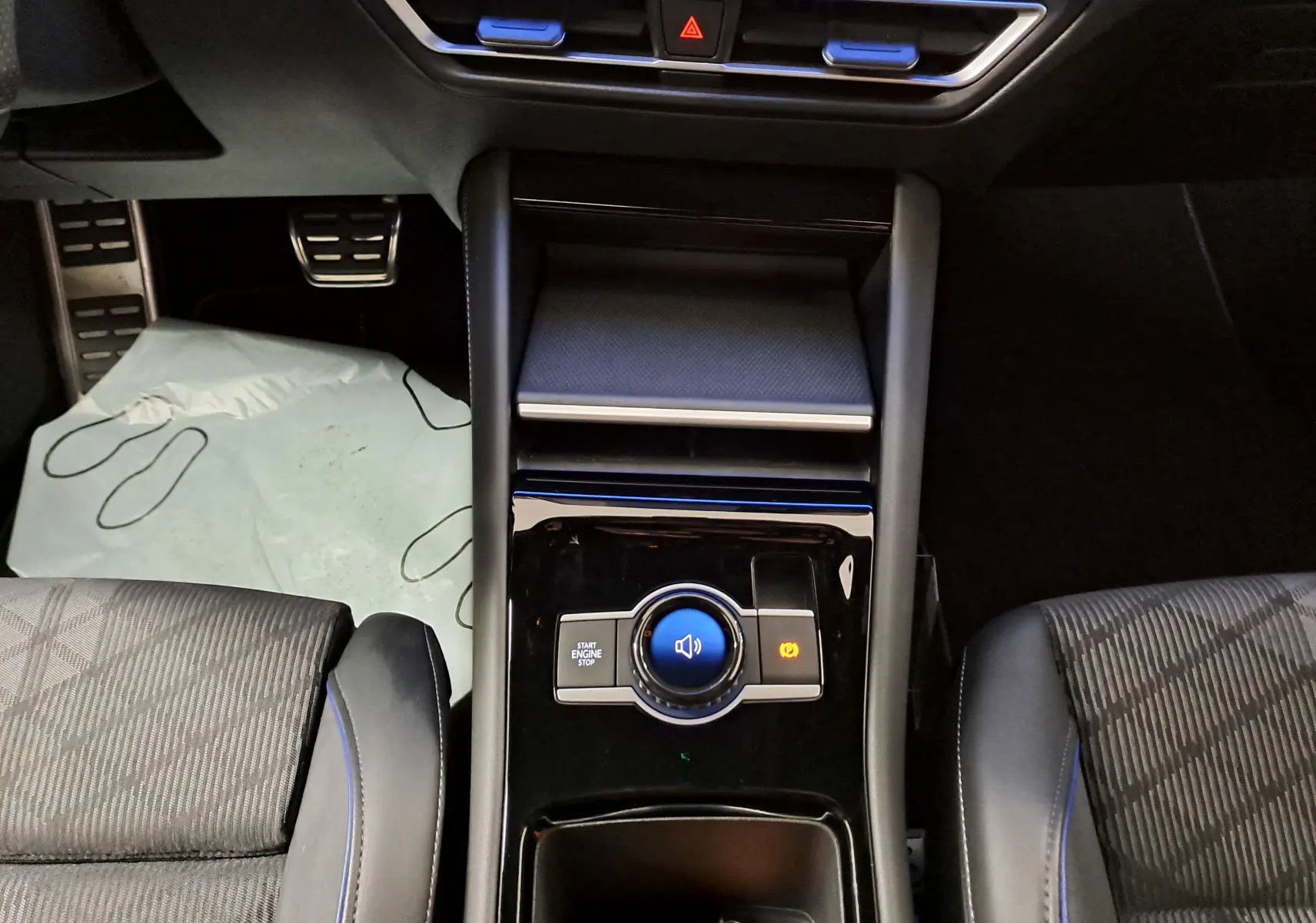Vue plongeante sur la console centrale noire du Volkswagen Tiguan 2025 avec commandes et sièges tissu gris à surpiqûres bleues.