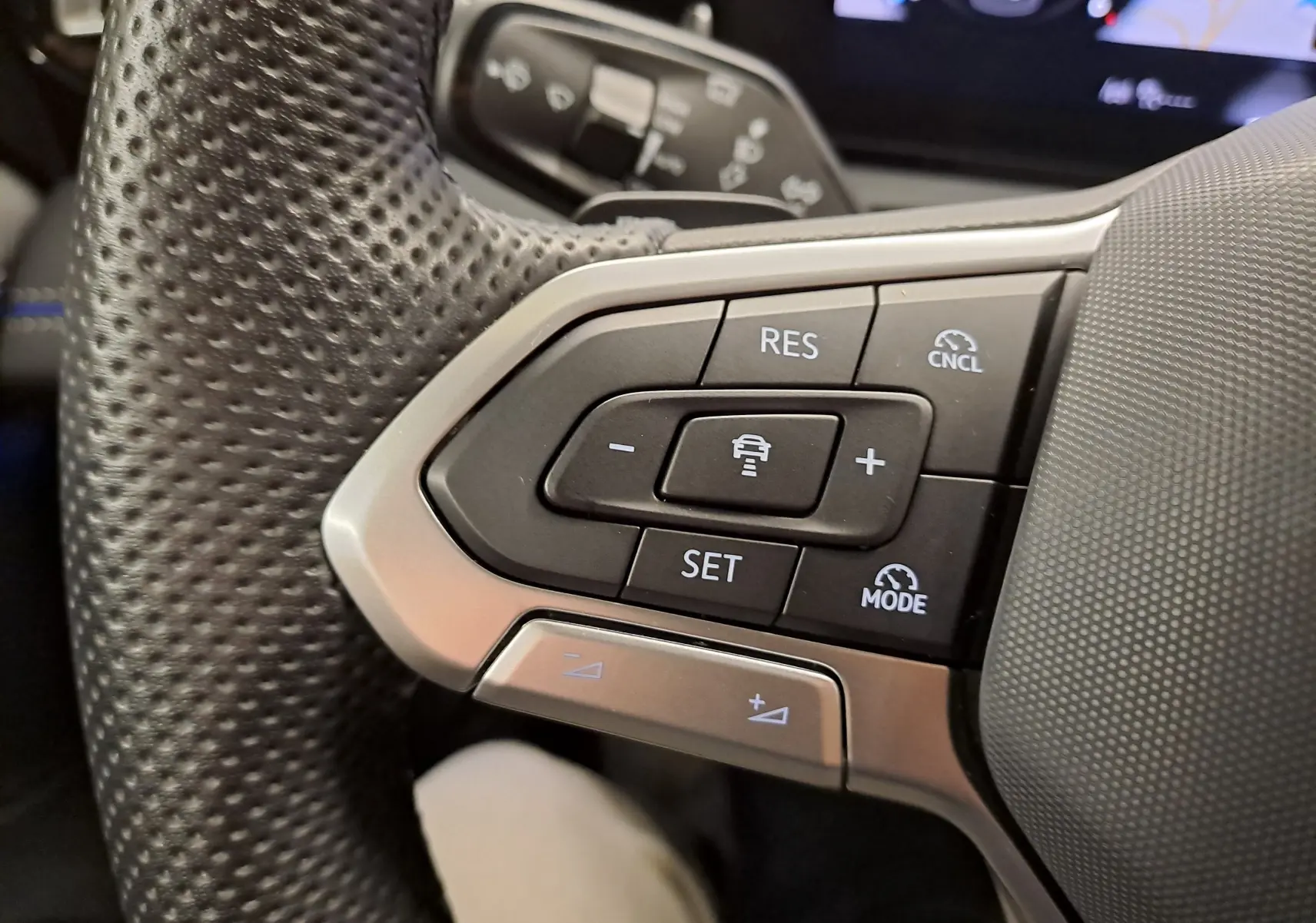 Gros plan sur les commandes du volant en cuir perforé du Volkswagen Tiguan 2.0 TDI 150 DSG7 R-Line, finition noire.