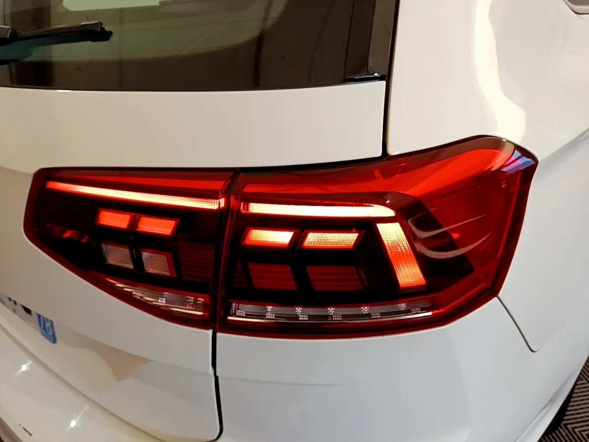 Gros plan sur les feux arrière allumés côté droit d'une Volkswagen Passat blanche hybride rechargeable.