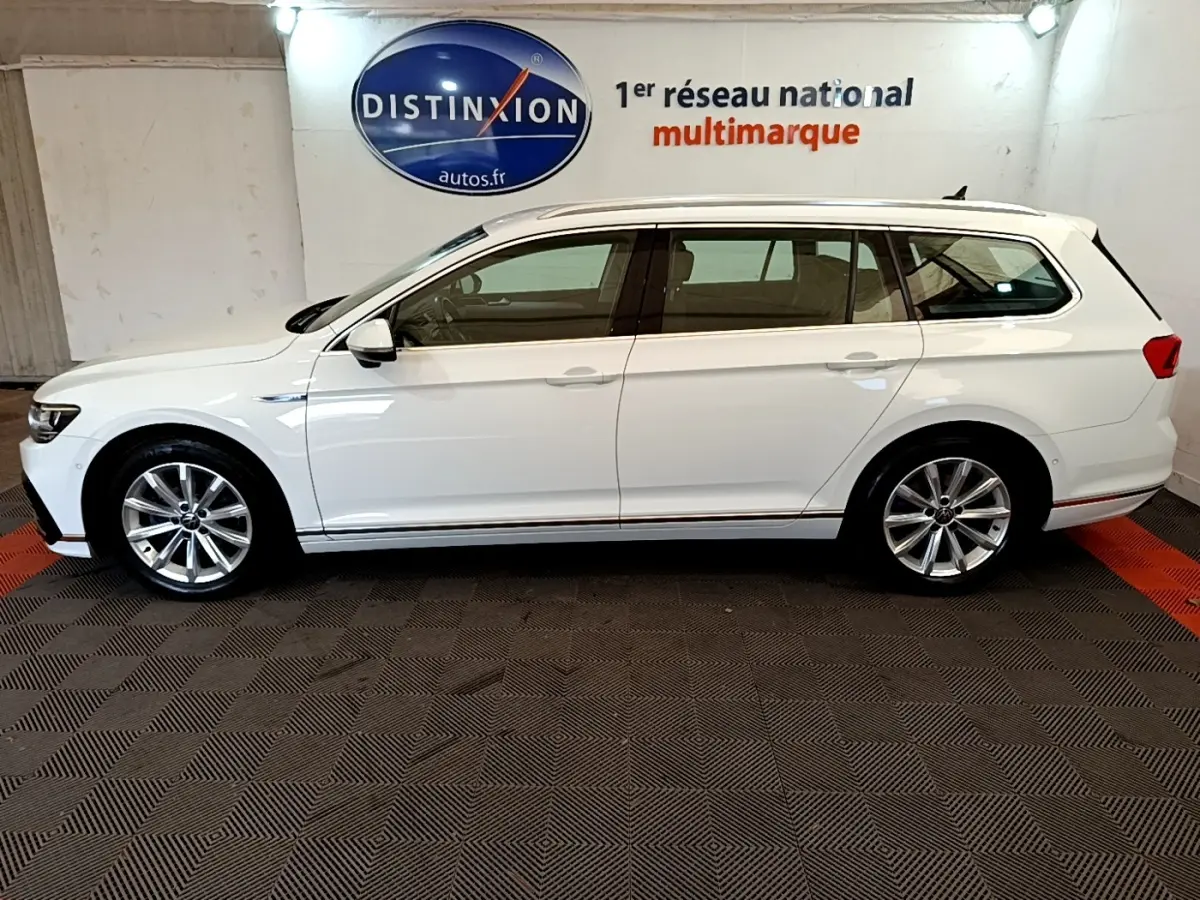 Volkswagen Passat break blanc vue de profil côté gauche, intérieur visible à travers les vitres teintées.