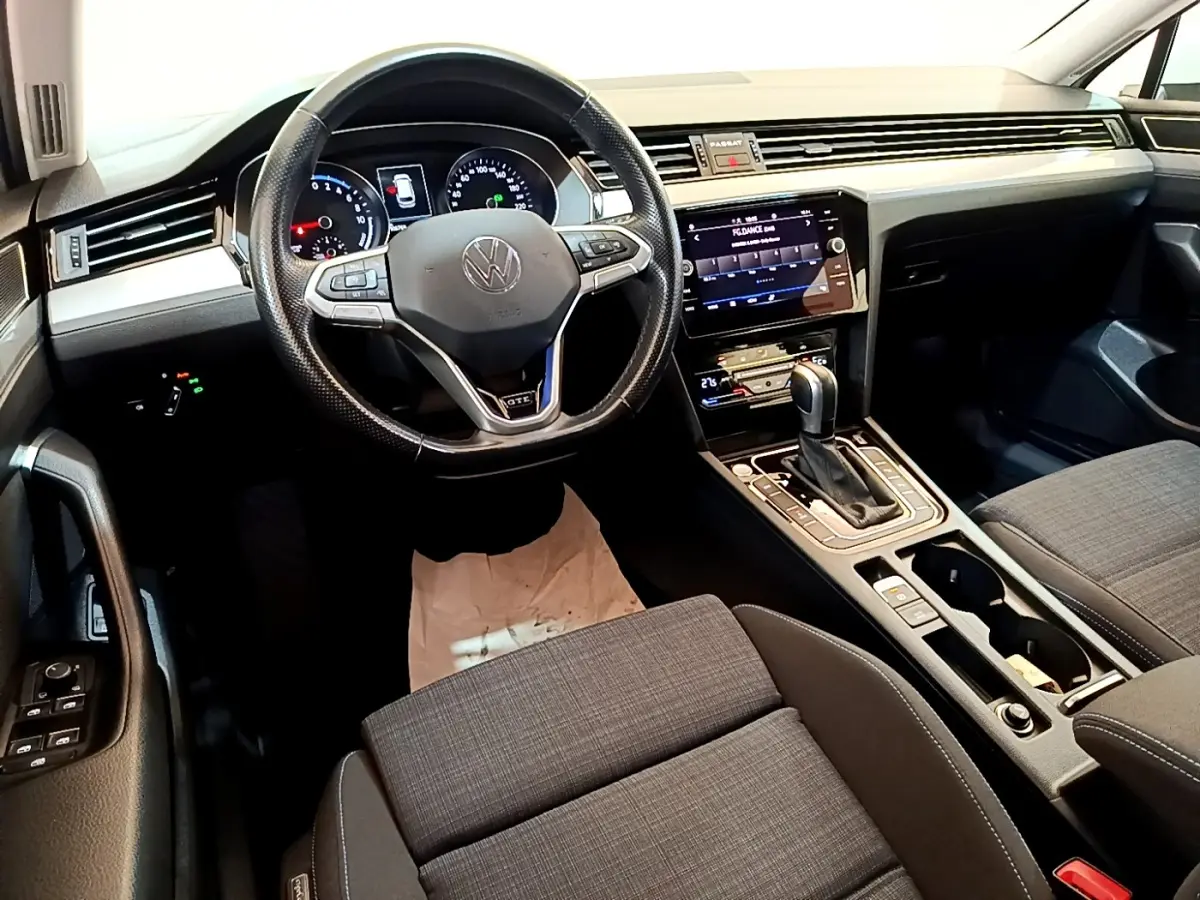 Vue intérieure de la Volkswagen Passat GTE 2021, tableau de bord et volant cuir noir avec écran tactile central.