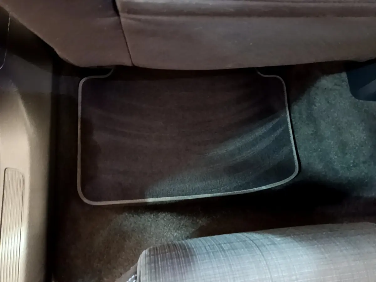 Tapis de sol noir sous le siège passager arrière d'une Volkswagen Passat blanche, vue intérieure au sol.