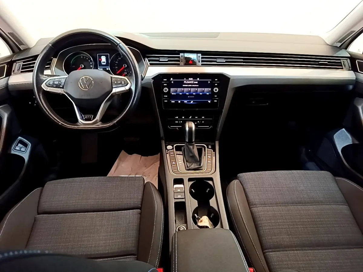 Vue intérieure avant de la Volkswagen Passat GTE 2021, tableau de bord noir avec écran tactile central et volant multifonctions.