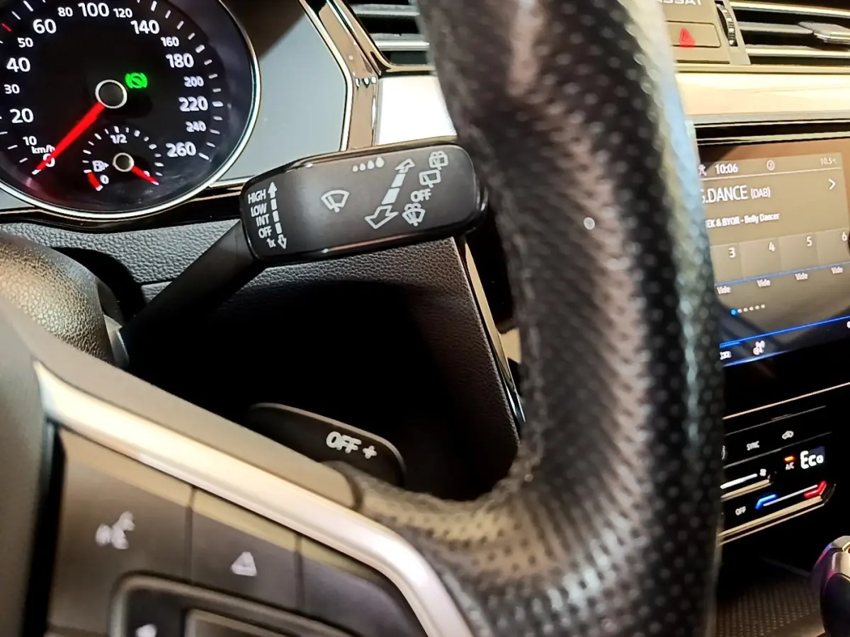 Gros plan intérieur sur le volant cuir noir et la commande d’essuie-glace de la Volkswagen Passat hybride blanche de 2021.