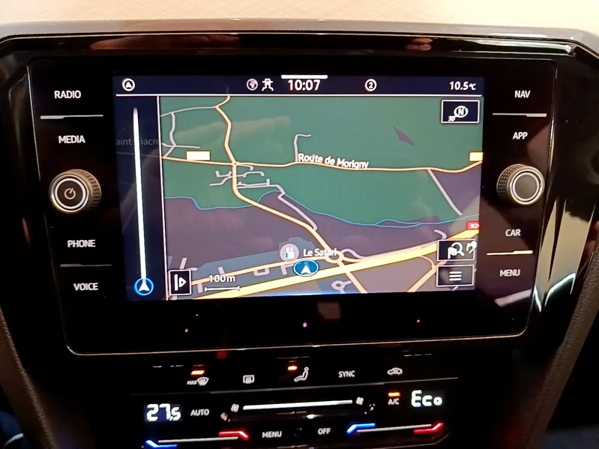 Vue rapprochée de l'écran tactile central du système de navigation d'une Volkswagen Passat blanche, affichant une carte routière.