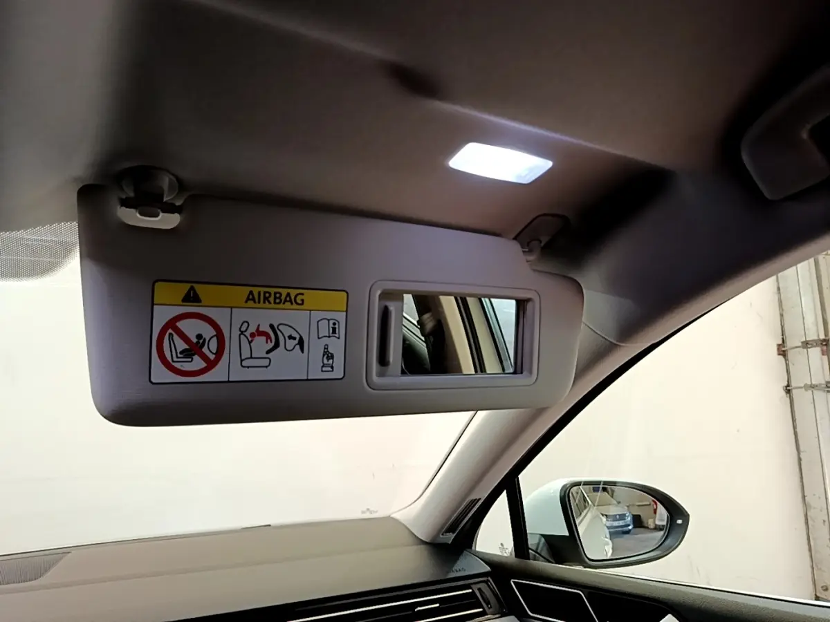 Intérieur de la Volkswagen Passat hybride 2021, vue côté passager avec pare-soleil abaissé et miroir éclairé.