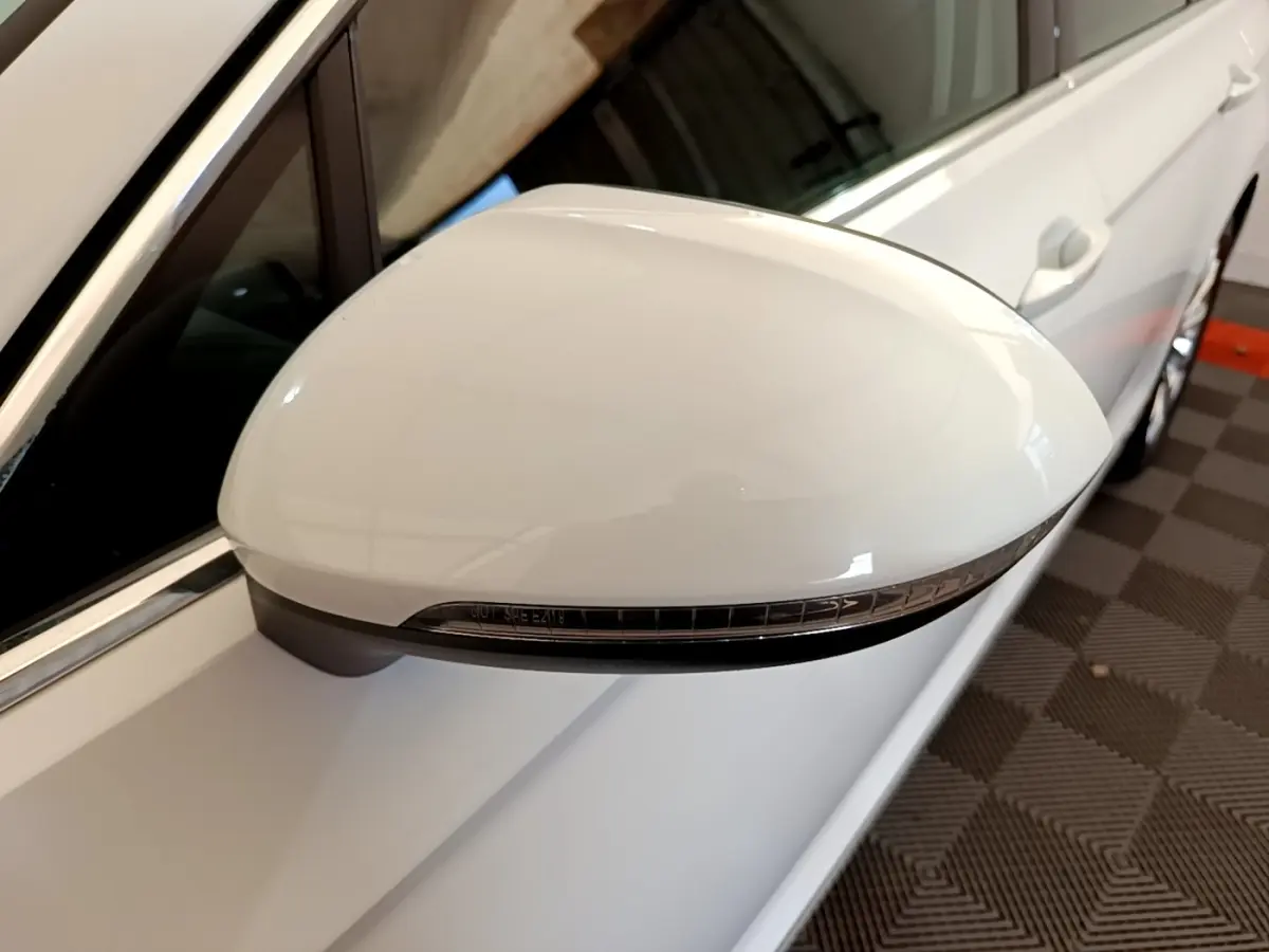 Rétroviseur blanc côté gauche de la Volkswagen Passat hybride 2021, avec clignotant intégré, vue rapprochée en intérieur.