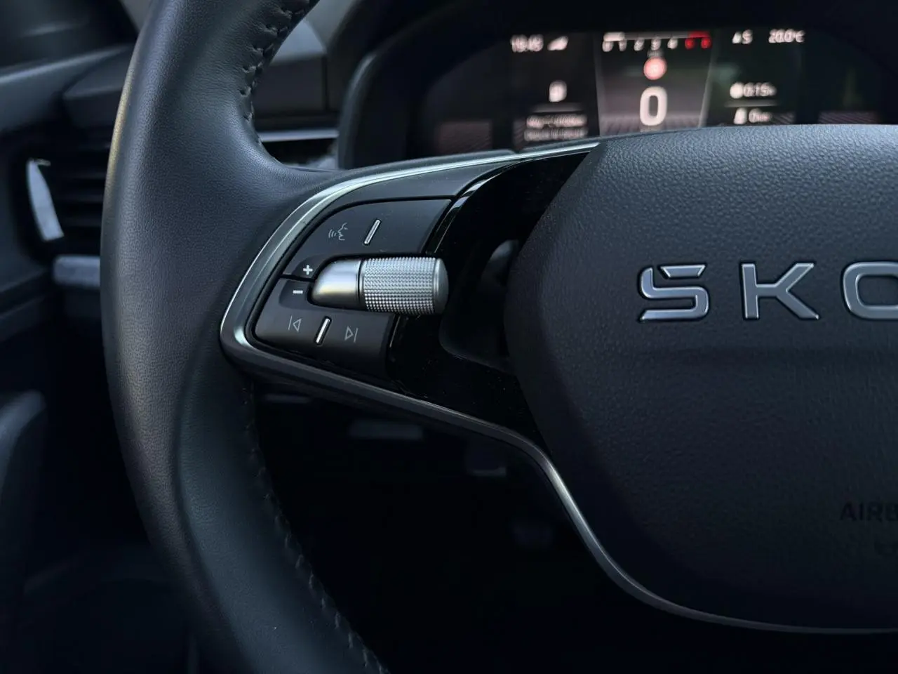 Gros plan sur le volant cuir noir de la Skoda Scala TSI 116, avec commandes multifonctions et affichage digital en arrière-plan.