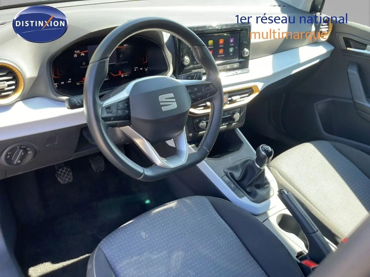 Vue intérieure de face du poste de conduite du SEAT Arona 2025, volant cuir multifonction et levier de vitesse manuel visibles.