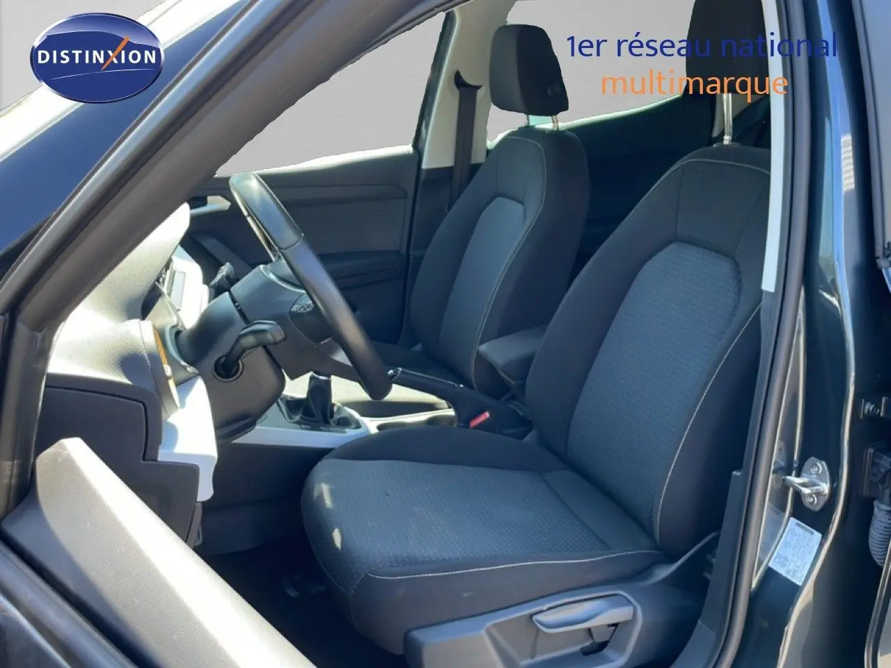 Vue intérieure côté conducteur du SEAT Arona 2025, montrant les sièges tissu noirs et le volant multifonction.