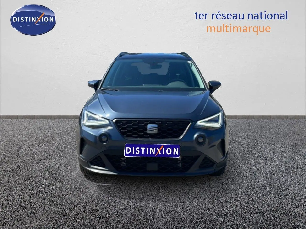 Vue avant d'un SEAT Arona gris Magnetic Metal avec toit noir, phares LED allumés sur fond neutre.
