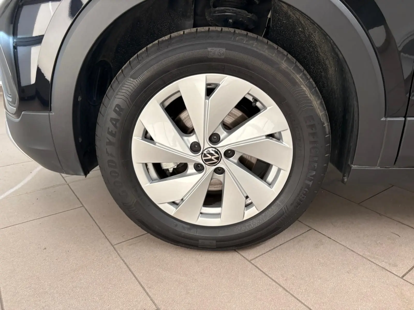 Gros plan sur la roue avant gauche du Volkswagen T-cross noir intense 2024 avec jante argentée et pneu Goodyear.