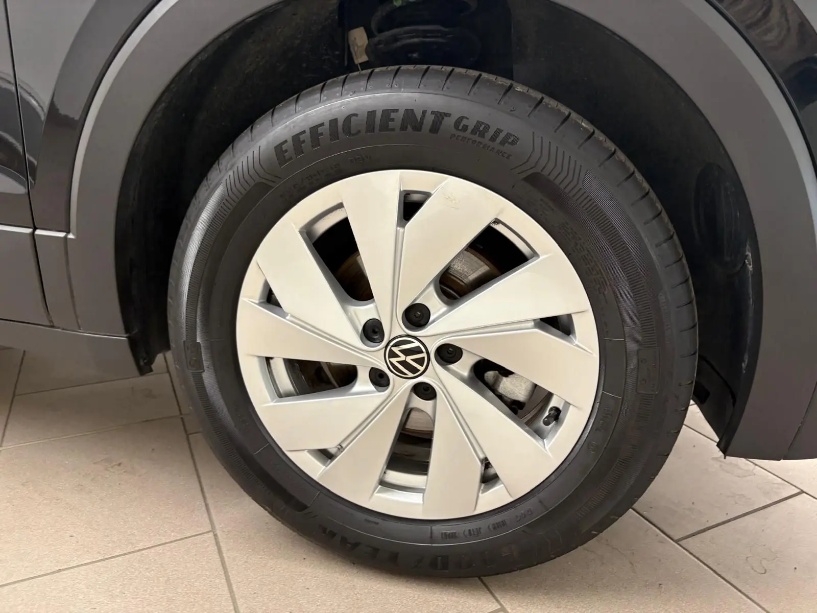 Gros plan sur la roue avant droite du Volkswagen T-Cross noir intense 2024 avec jante alliage et pneu EfficientGrip.