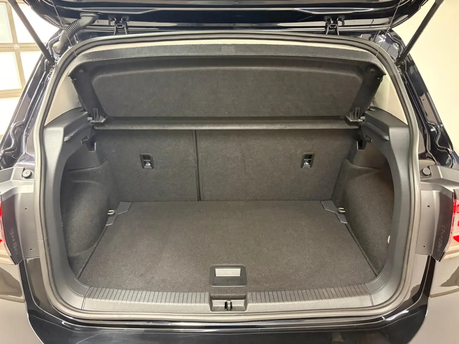 Coffre ouvert vu de l'arrière d'un Volkswagen T-Cross noir intense 2024, intérieur spacieux et bien fini.