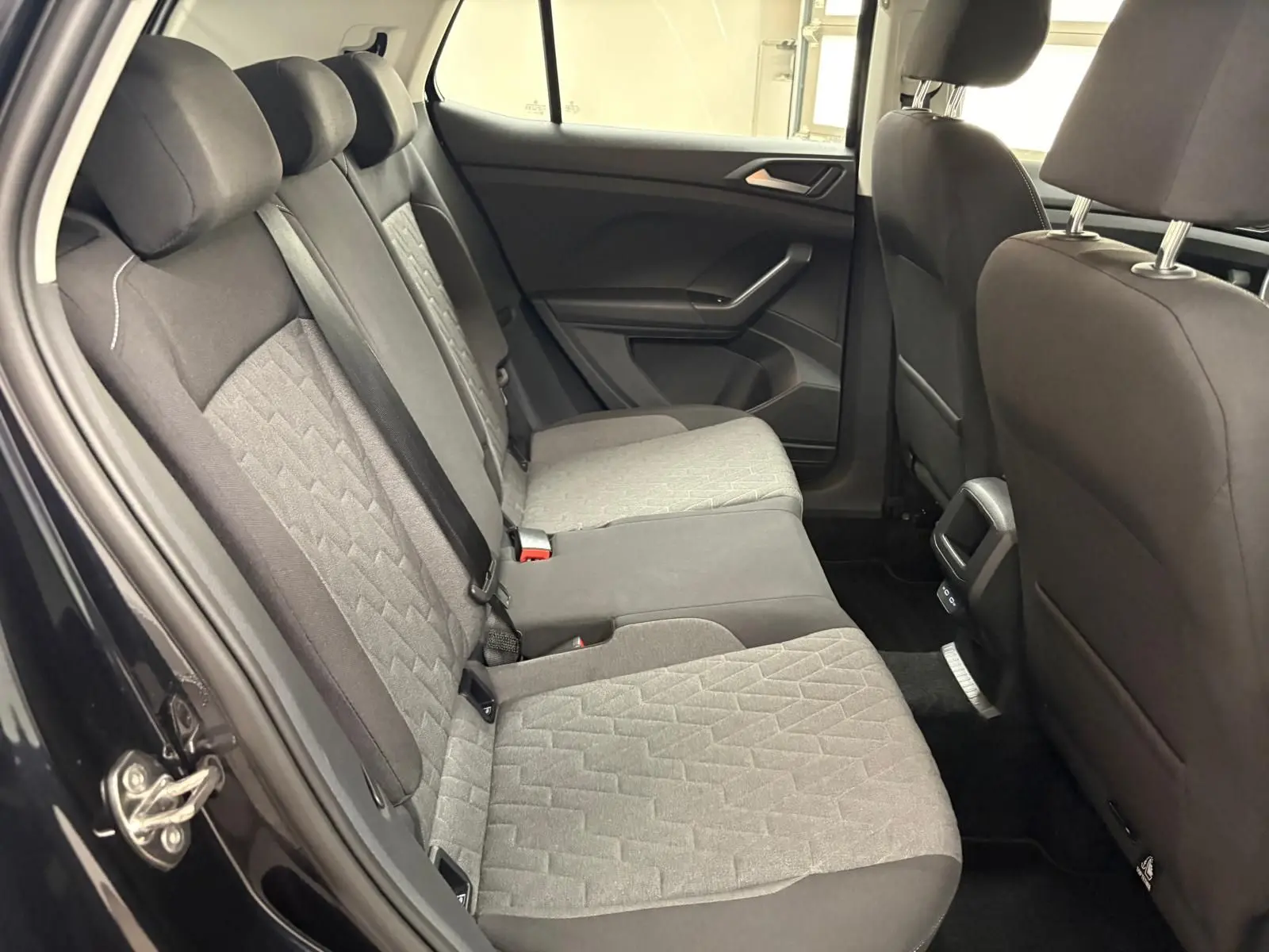 Vue intérieure arrière côté gauche du Volkswagen T-Cross 2024 noir intense, montrant les sièges arrière en tissu gris et noir.