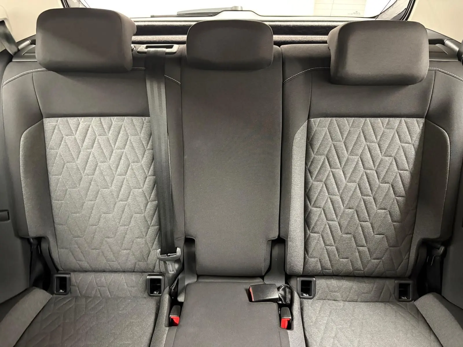 Vue intérieure arrière des sièges arrière du Volkswagen T-Cross 2024 avec tissu gris à motifs géométriques et appuie-têtes noirs.