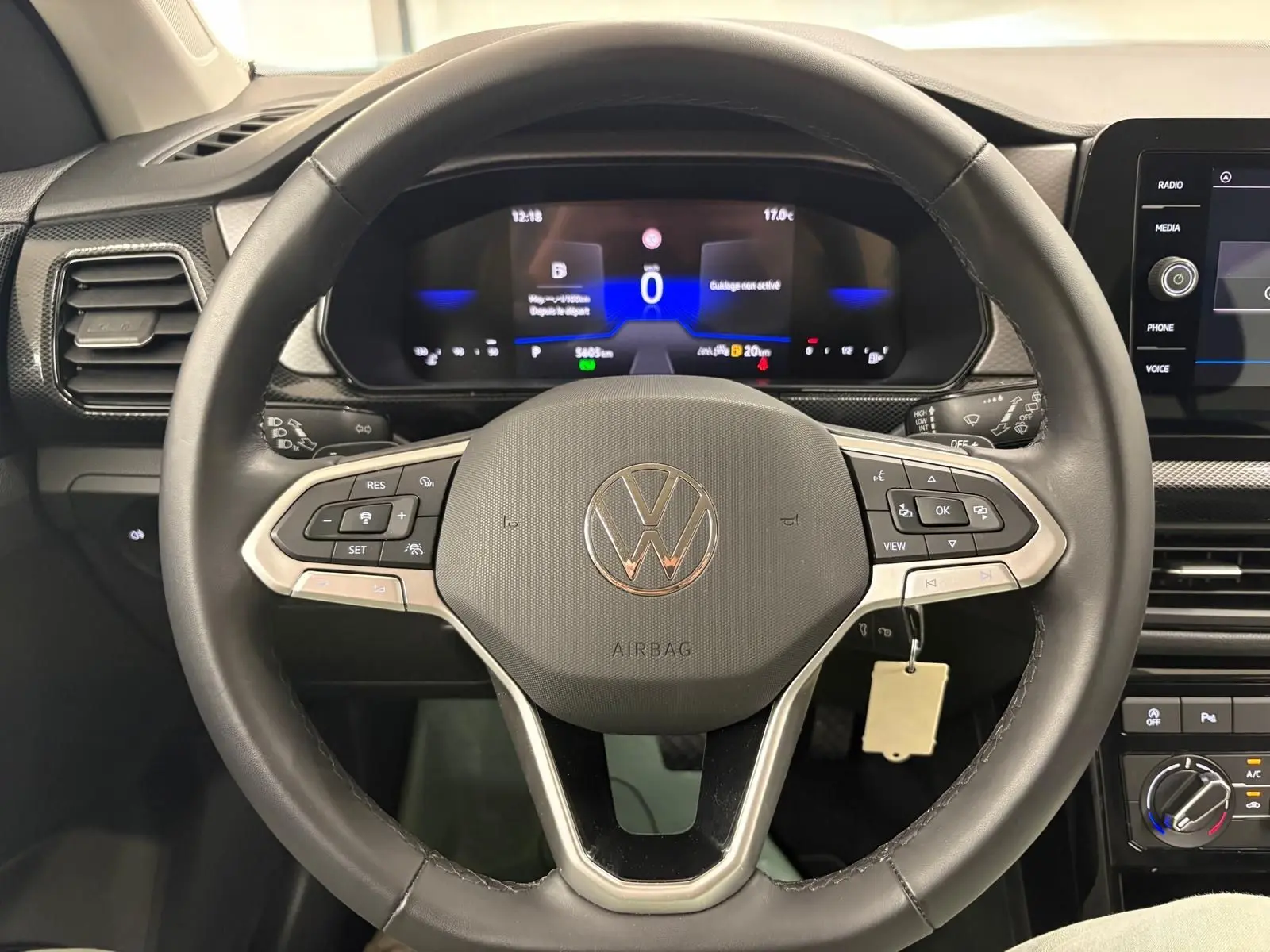 Vue rapprochée du volant noir du Volkswagen T-Cross 2024 avec tableau de bord numérique et commandes intégrées.