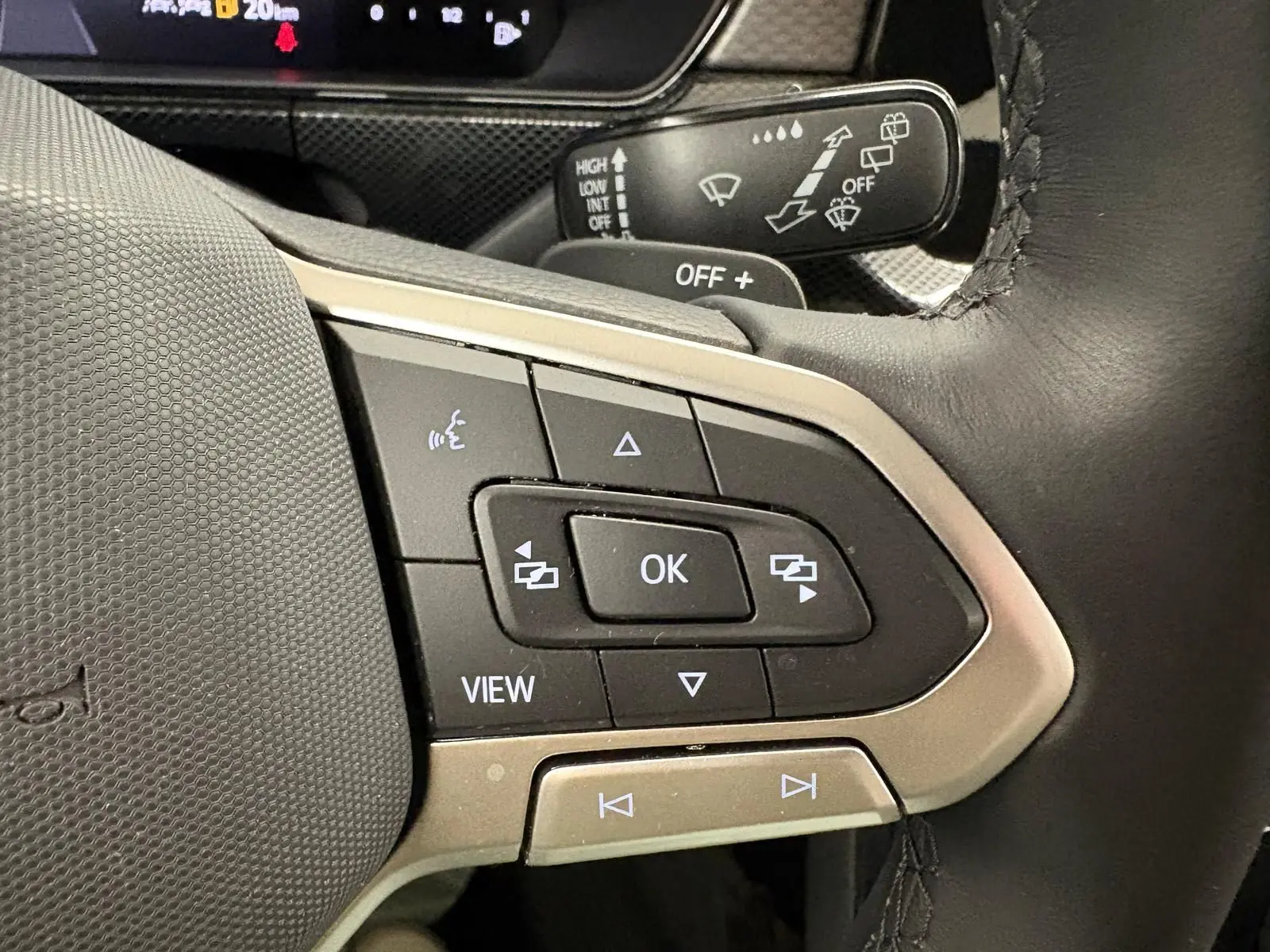 Gros plan sur les commandes au volant du Volkswagen T-Cross 2024 noir intense, avec boutons multifonctions et levier d'essuie-glace.