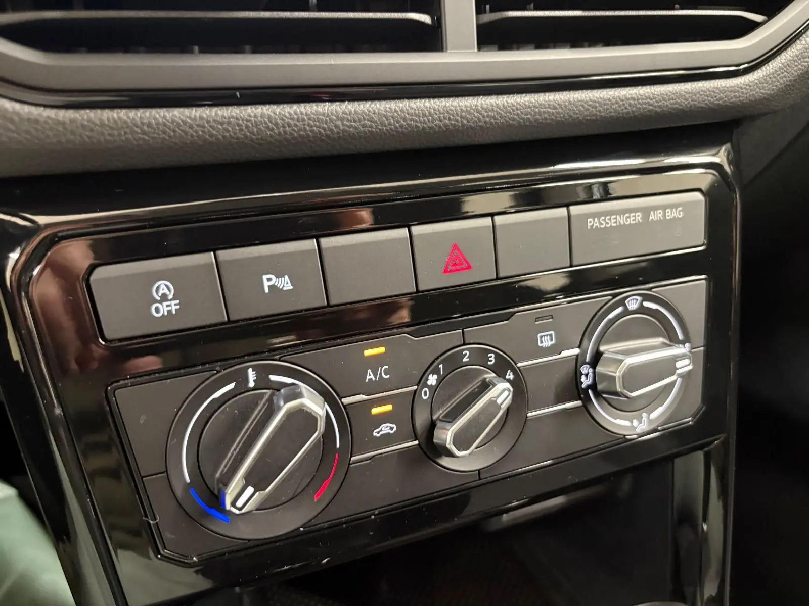 Gros plan sur les commandes de climatisation et sécurité du tableau de bord noir du Volkswagen T-Cross 2024.