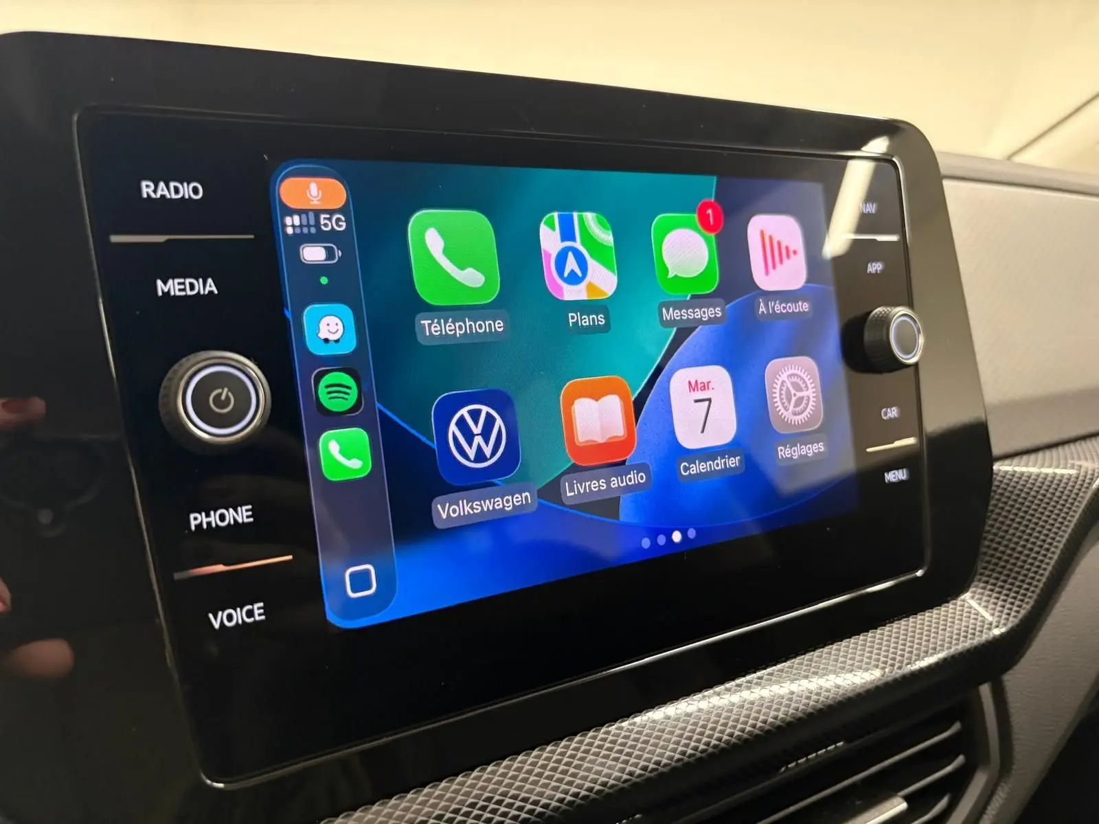 Écran tactile central du Volkswagen T-cross 2024 affichant les applications connectées, avec commandes autour et finition intérieure claire.