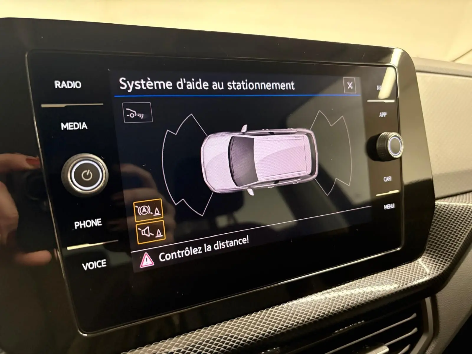 Écran tactile du système d'aide au stationnement du Volkswagen T-Cross 2024 affichant une vue aérienne du véhicule.