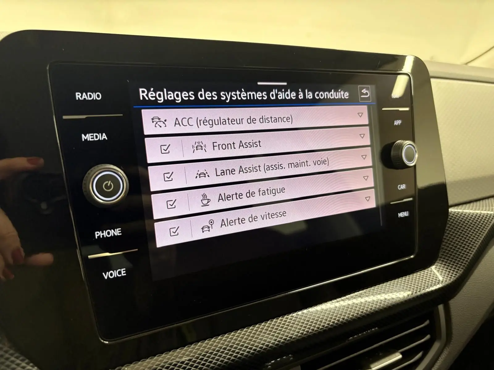 Écran tactile central du Volkswagen T-Cross 2024 affichant les réglages des aides à la conduite dans un intérieur clair.