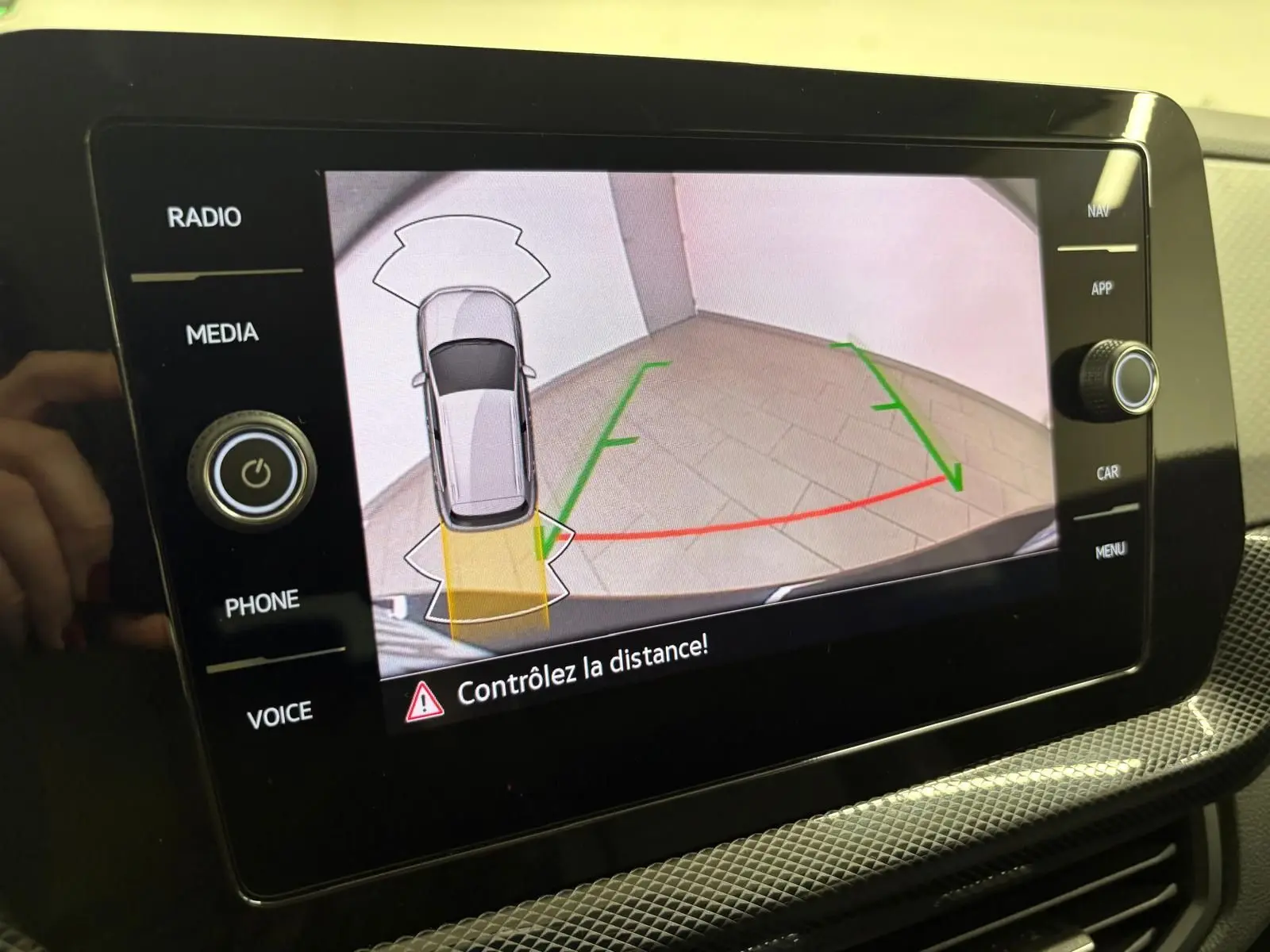 Écran multimédia du Volkswagen T-cross 2024 montrant l'aide au stationnement avec vue arrière et lignes de guidage colorées.